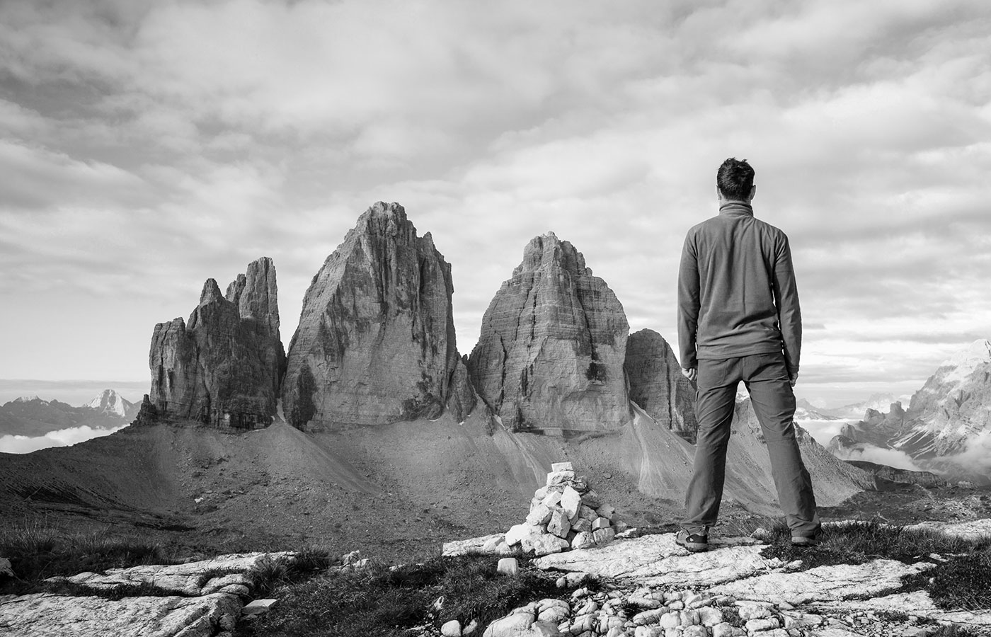 Foto in bianco e nero di un uomo in piedi di spalle che ammira le tre cime di Lavaredo nelle Dolomiti di Sesto